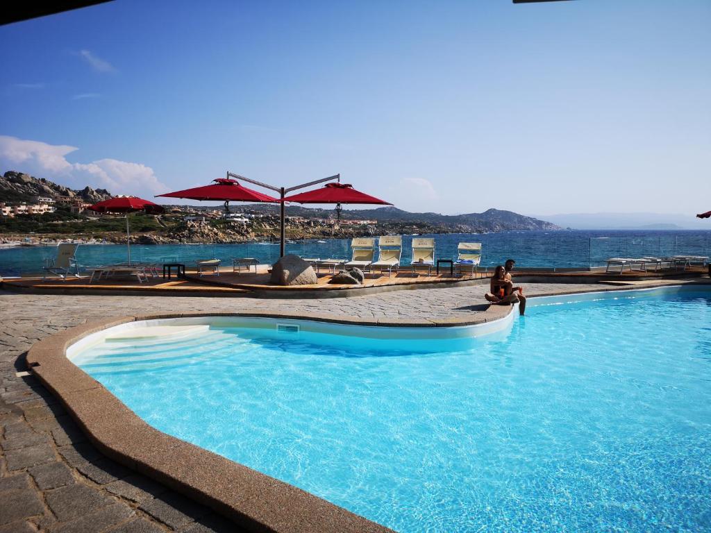 une personne est assise à côté d'une piscine dans l'établissement Club Esse Shardana, à Santa Teresa Gallura
