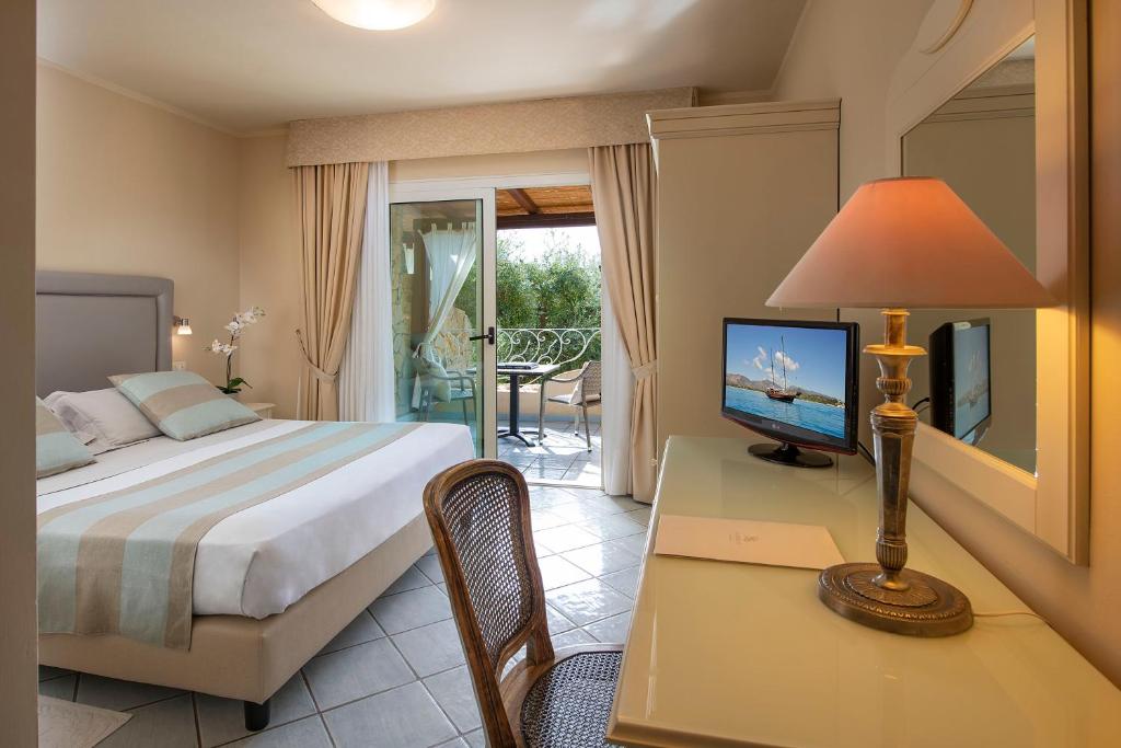 une chambre avec un lit et un bureau avec une télévision dans l'établissement Boutique Hotel Su Sergenti, à Villasimius