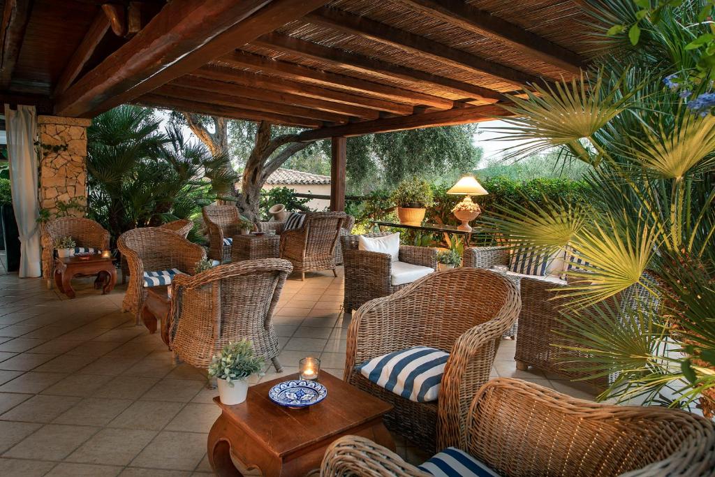une terrasse avec des chaises en osier et une table avec une bougie dans l'établissement Boutique Hotel Su Sergenti, à Villasimius