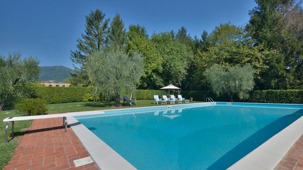 - une piscine dans une cour avec des chaises et des arbres dans l'établissement Villa Alida 12, Emma Villas, à Capannori
