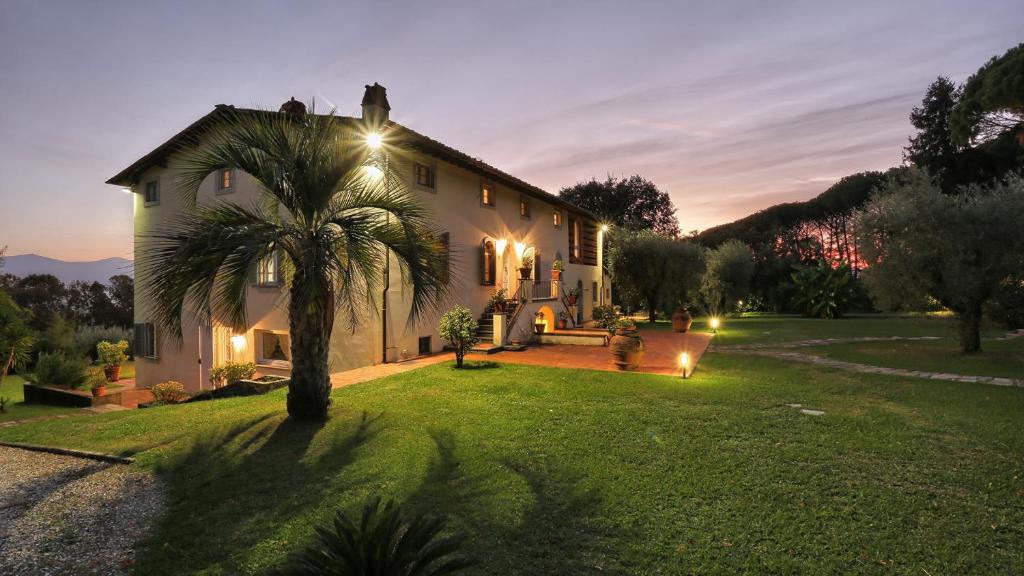 une maison avec un palmier dans la cour la nuit dans l'établissement Villa Alida 12, Emma Villas, à Capannori