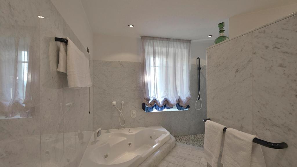 La salle de bains blanche est pourvue d'une baignoire et d'une fenêtre. dans l'établissement Villa Alida 12, Emma Villas, à Capannori