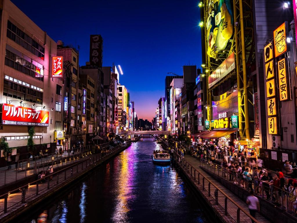 un bateau dans une rivière dans une ville la nuit dans l'établissement Kaneyoshi Ryokan, à Osaka