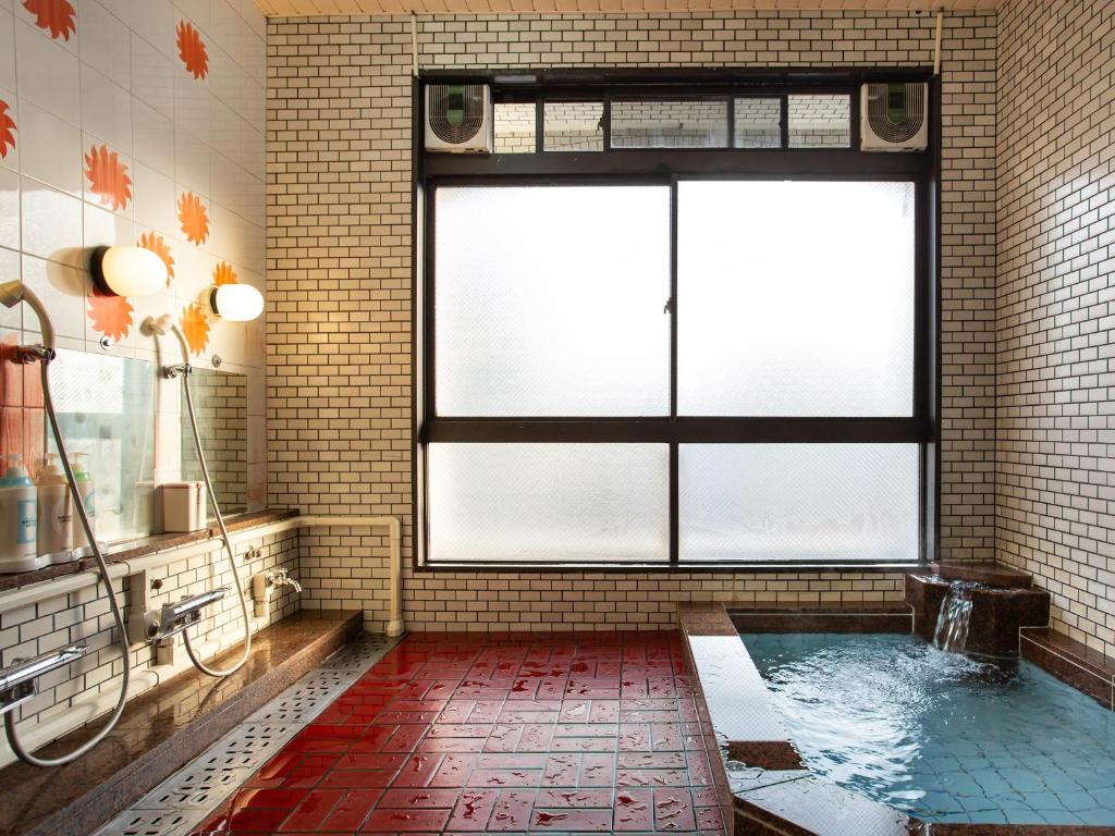 La salle de bains est pourvue d'une baignoire et d'une fenêtre. dans l'établissement Kaneyoshi Ryokan, à Osaka