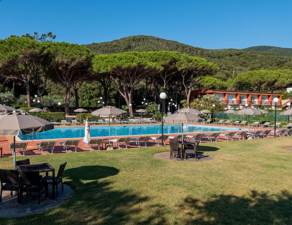 - une piscine avec des tables et des parasols à côté d'un complexe dans l'établissement Hotel Desiree, à Procchio