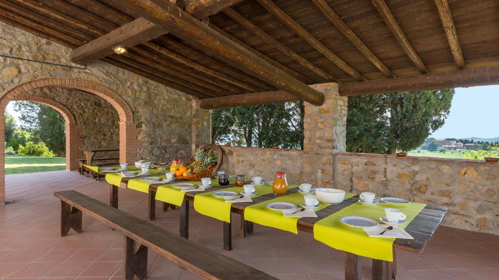 une longue table avec des chaises jaunes sur une terrasse dans l'établissement Podere Calcheto 14, Emma Villas, à Montecatini Val di Cecina