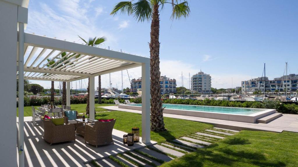 un patio avec des palmiers et une piscine dans l'établissement PORTOVERDE BEACH VILLA 12, Emma Villas, à Misano Adriatico