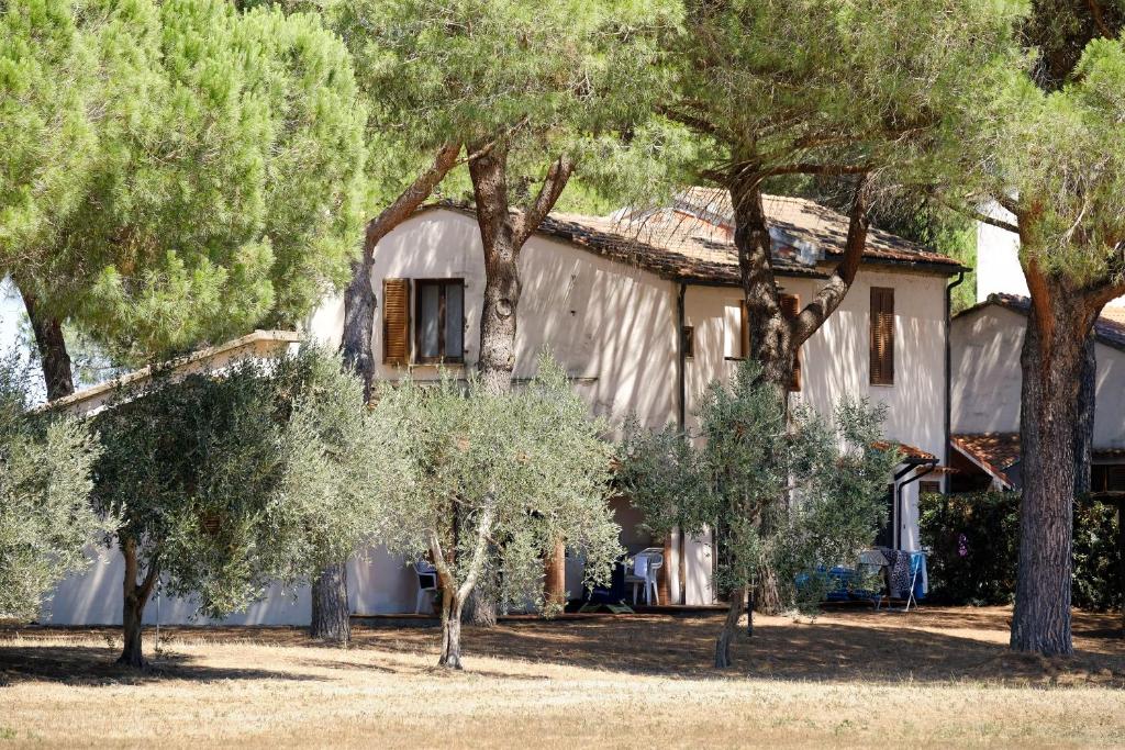 une maison avec des arbres devant elle dans l'établissement Residence La Canova II, à Marina di Grosseto