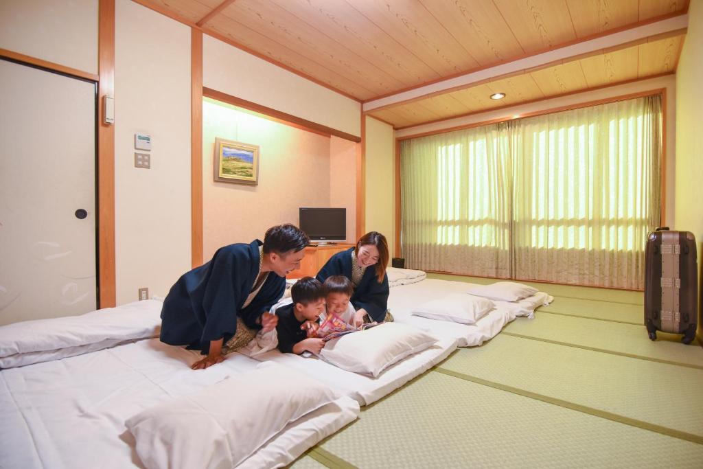 un homme, une femme et un enfant sur un lit dans l'établissement Hiroshima no Yado Aioi, à Hiroshima