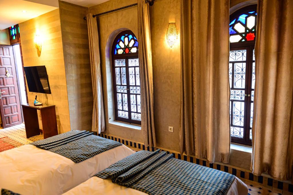 une chambre avec deux lits et deux fenêtres dans l'établissement Riad Al mazhar, à Rabat