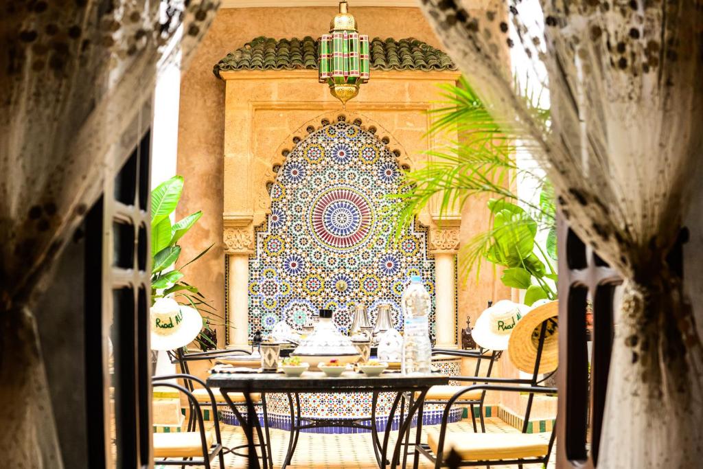 une table et des chaises devant un mur orné d'une fresque murale dans l'établissement Riad Al mazhar, à Rabat