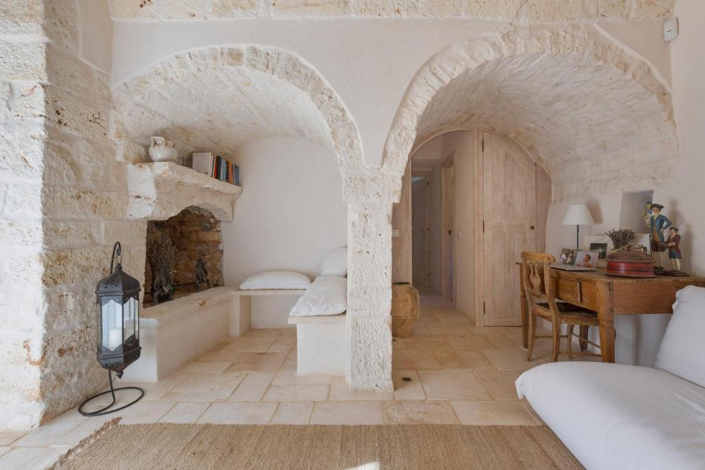 une chambre avec un lit et une table dans une pièce dans l'établissement Trullo dell'Oleandro - Le Corti del Silenzio, à Ceglie Messapica