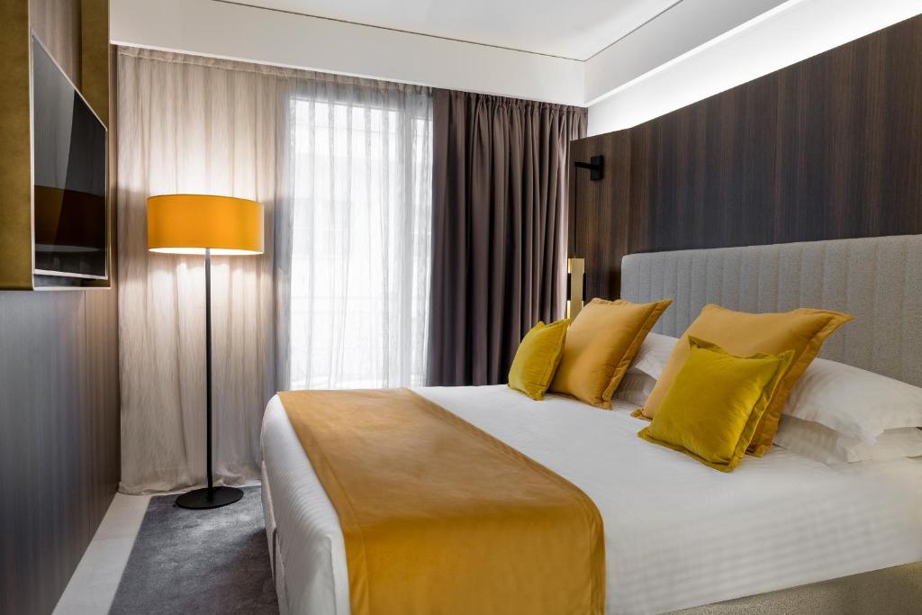 une chambre avec un grand lit avec des oreillers jaunes dans l'établissement We Me Suite Hotel, à Riccione