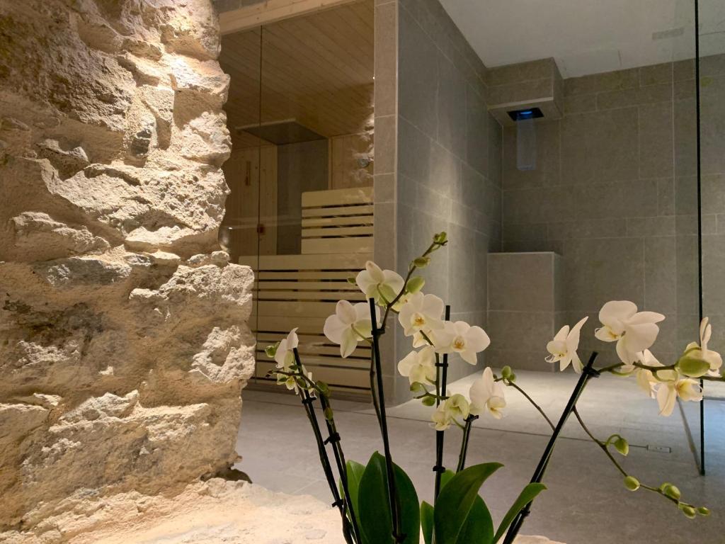 un vase avec des fleurs blanches devant une salle de bains dans l'établissement Spa & Wellness by Des Anglais " Accesso SPA compreso", à Sanremo
