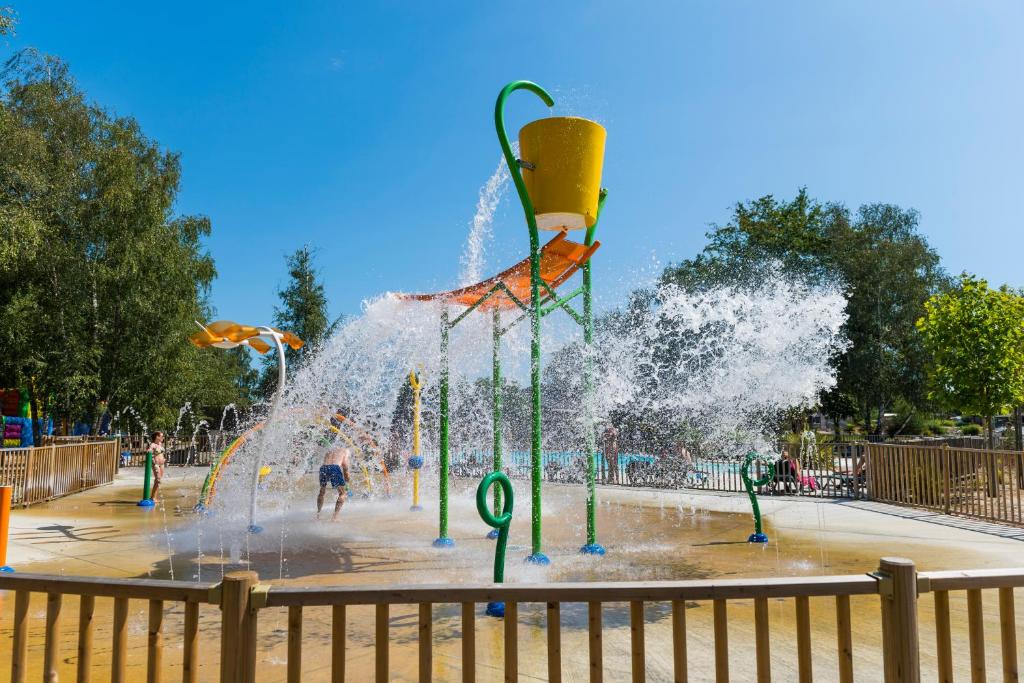 Une fontaine dans un parc avec des gens qui y jouent dans l'établissement Mobil Home XXL2 4 chambres - Camping Bordeaux Lac, à Bruges