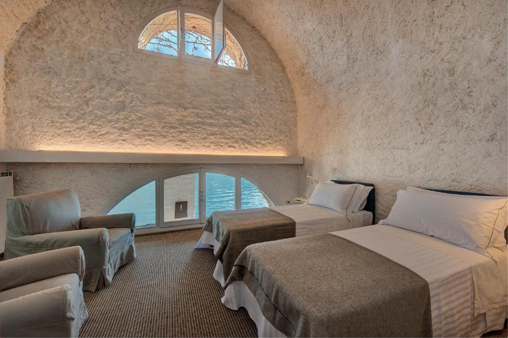 une chambre avec deux lits et une chaise et une fenêtre dans l'établissement La Filanda - The House Of Travelers, à Brienno 77 autres photos