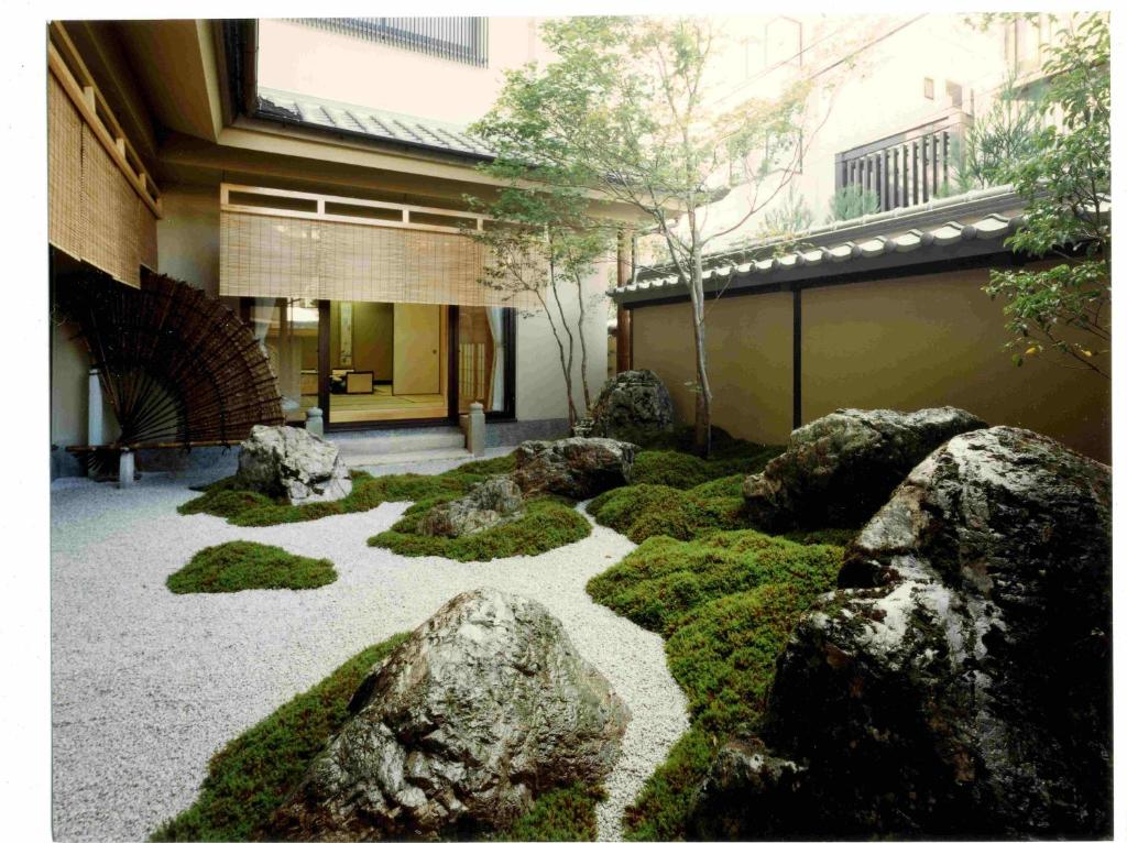un jardin avec des rochers et des mousses en face d'un bâtiment dans l'établissement Kyoto Ryokan Kinoe, à Kyoto