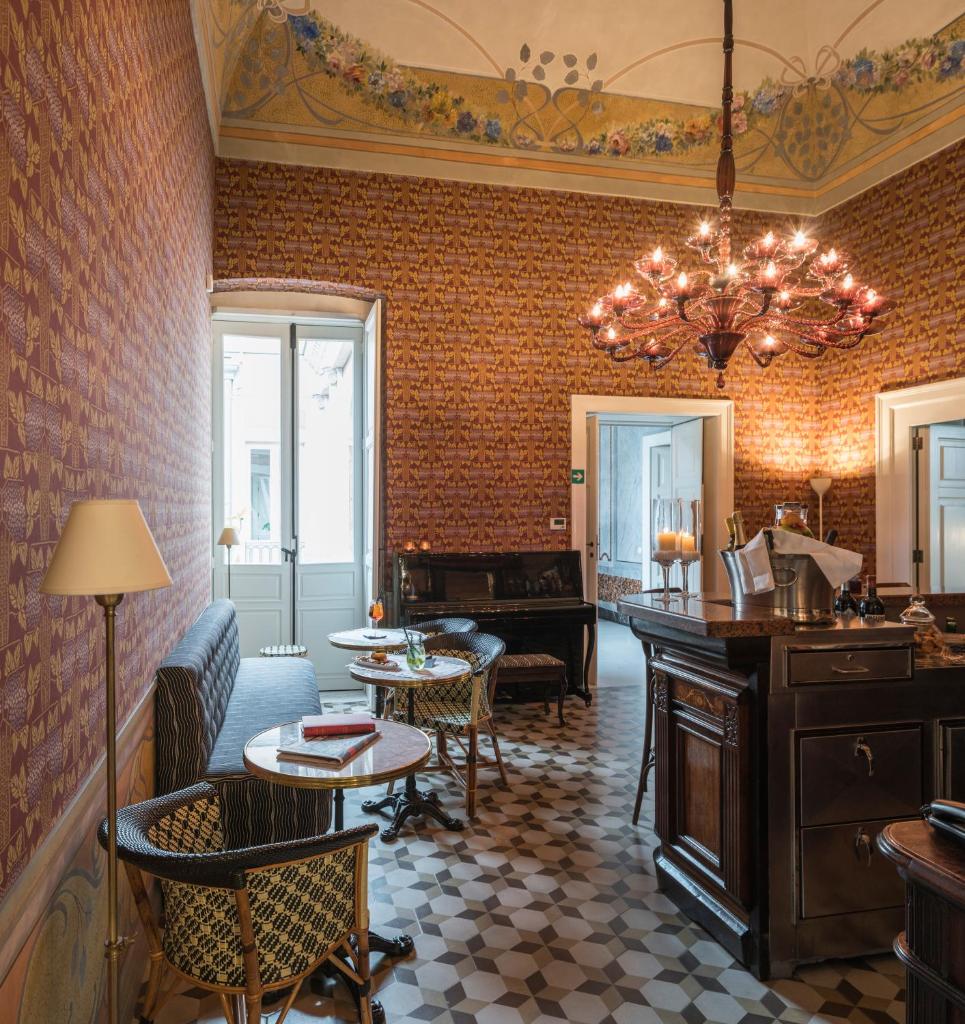 un salon avec un lustre et un piano dans l'établissement Palazzo Margherita, à Bernalda