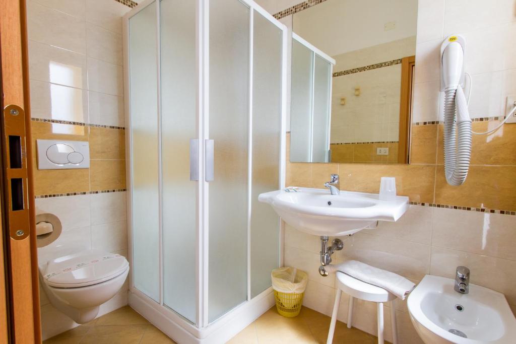 une salle de bain avec un lavabo, des toilettes et un miroir dans l'établissement Hotel Monica, à Rimini