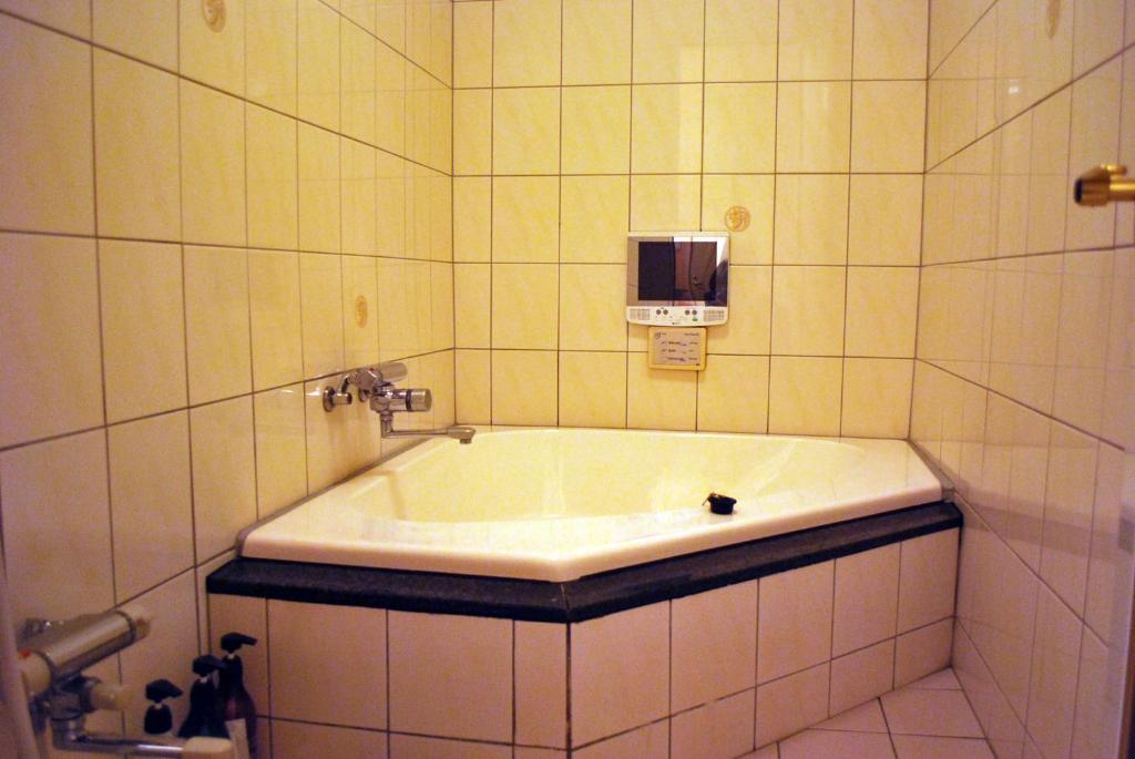 une salle de bain avec baignoire dans une pièce carrelée dans l'établissement Ena Hotel Venus, à Ena