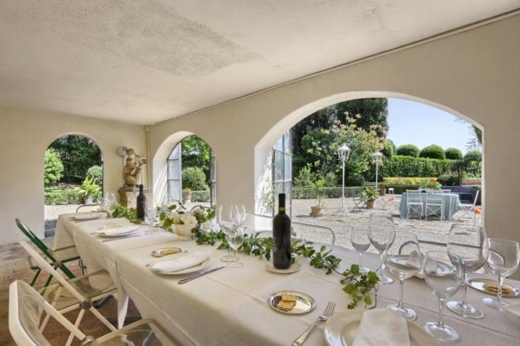 une salle à manger avec une grande table et des chaises blanches dans l'établissement VIlla Merlo Ner0, à Florence