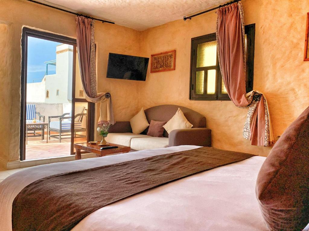 une chambre avec un lit, un canapé et une fenêtre dans l'établissement Riad Al Madina, à Essaouira