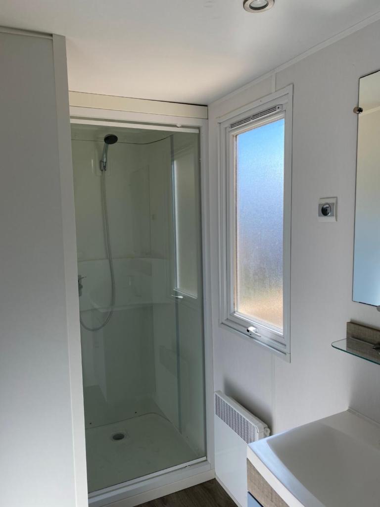 La salle de bains est pourvue d'une douche en verre et d'une fenêtre. dans l'établissement Le Solèou, à Port-la-Nouvelle