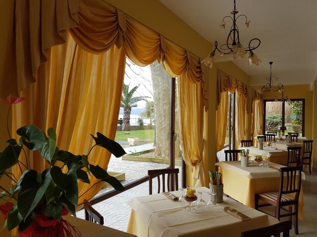 d'une salle à manger avec des tables ornées de rideaux jaunes. dans l'établissement Hotel Eden Sul Lago, à Bolsena