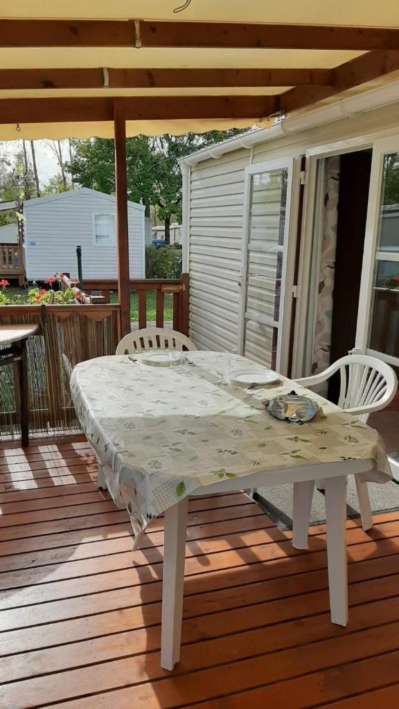 une table et des chaises blanches sur une terrasse en bois dans l'établissement Assist' Mobil Home 262 - Mobil Home Excellence Bora Bora 3 chambres, à Onzain 7 autres photos