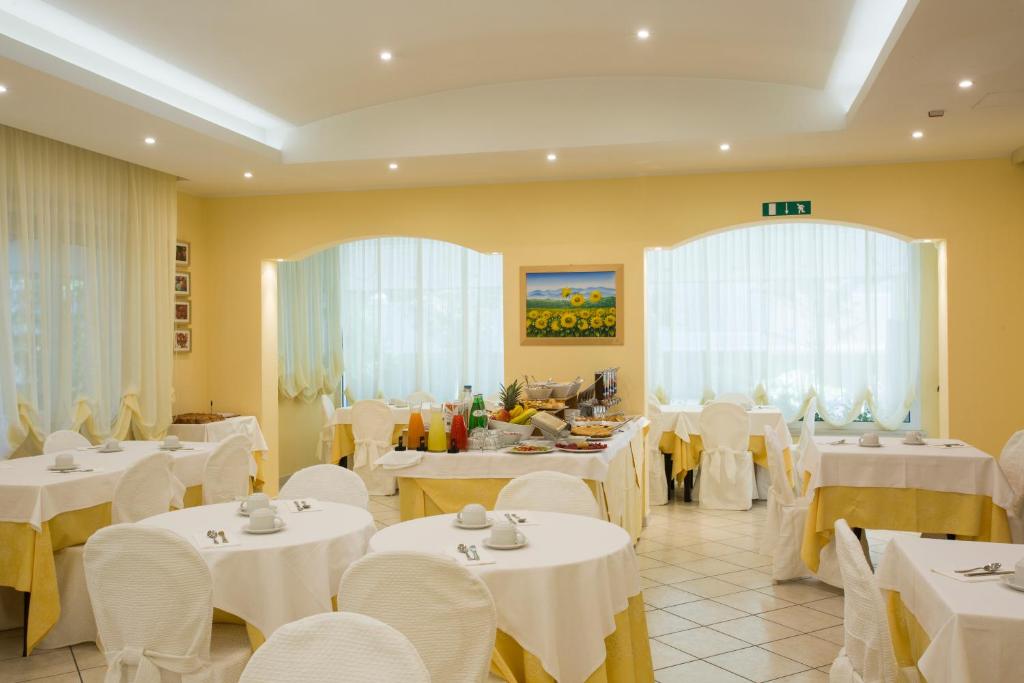 une salle à manger avec des tables blanches et des chaises blanches dans l'établissement Mansarda Cannes, à Riccione