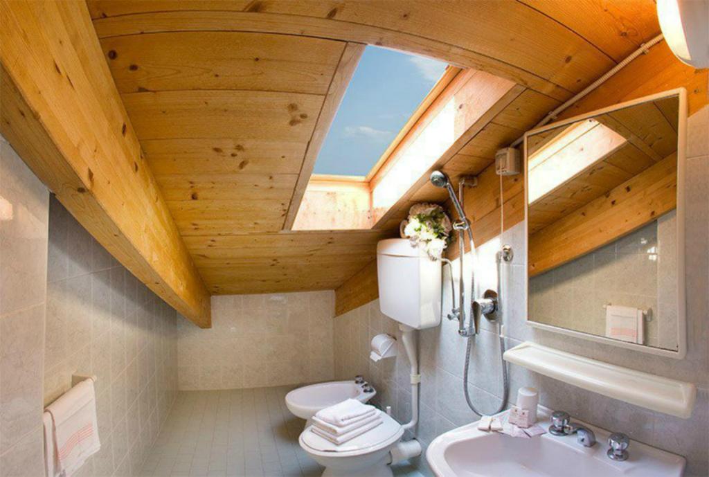 une salle de bain avec WC et lavabo avec puits de lumière dans l'établissement Mansarda Cannes, à Riccione