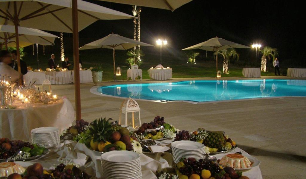 une table avec des assiettes de nourriture à côté d'une piscine dans l'établissement Hotel San Giorgio, à Crotone