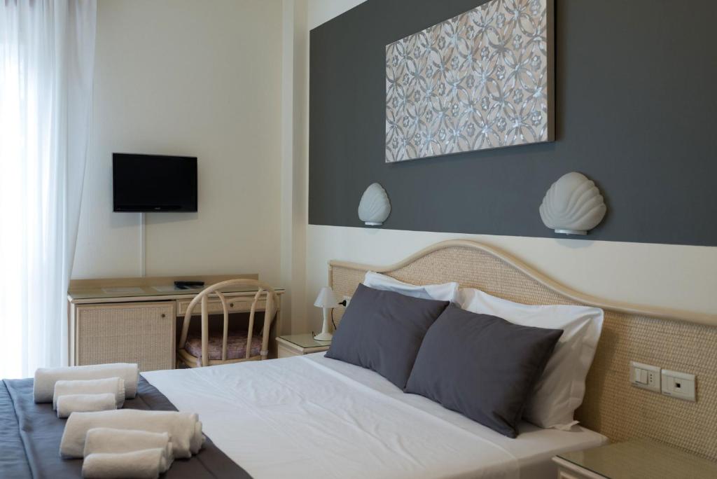 une chambre avec un lit et un bureau avec une télévision dans l'établissement Hotel Airone, à Bibione