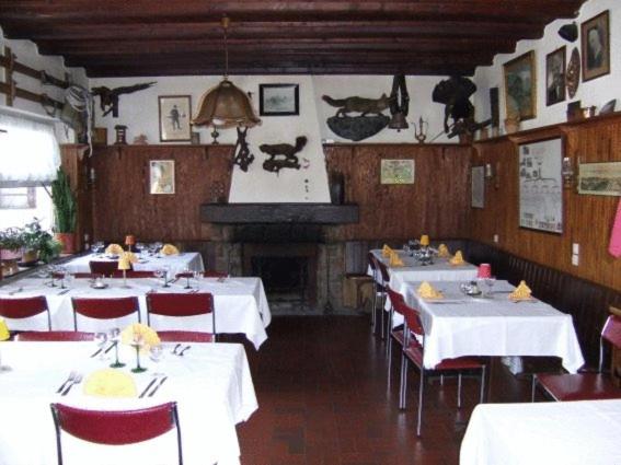 une salle à manger avec des tables et des chaises blanches ainsi qu'une cheminée dans l'établissement Hôtel Restaurant Wolf, à Le Markstein