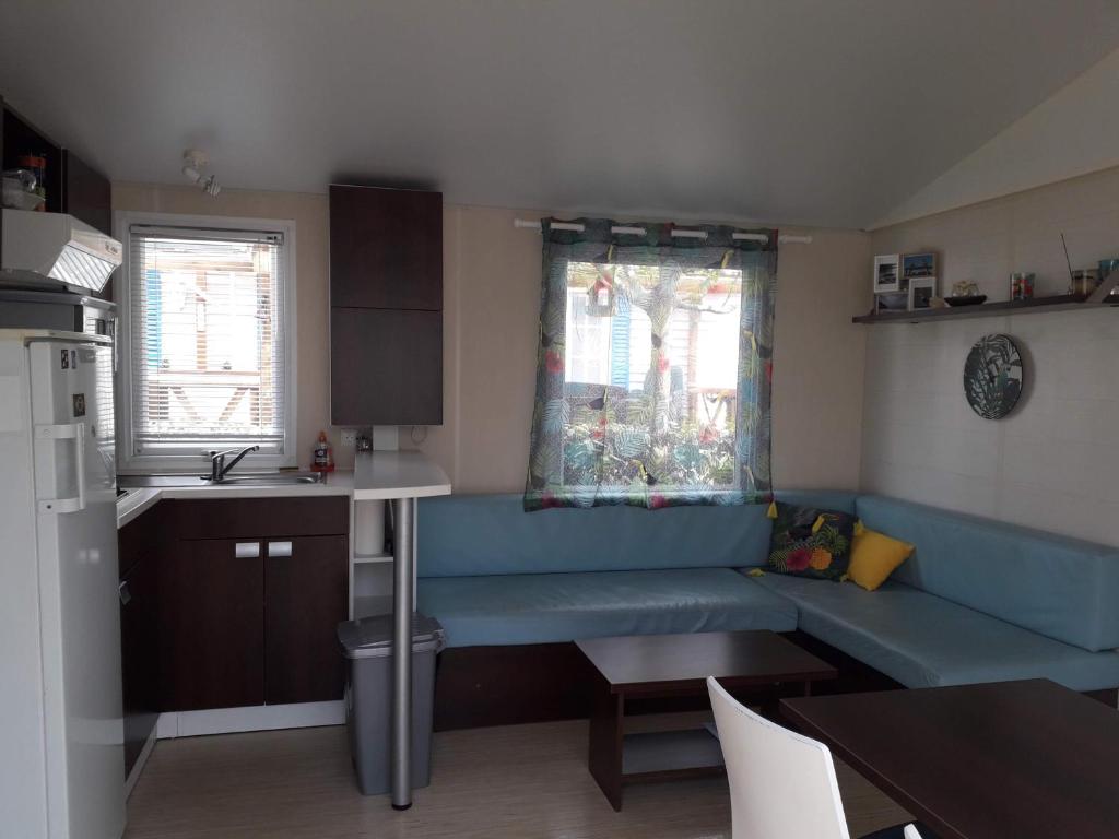 un salon avec un canapé bleu dans une cuisine dans l'établissement mobil home, à Lacanau-Océan