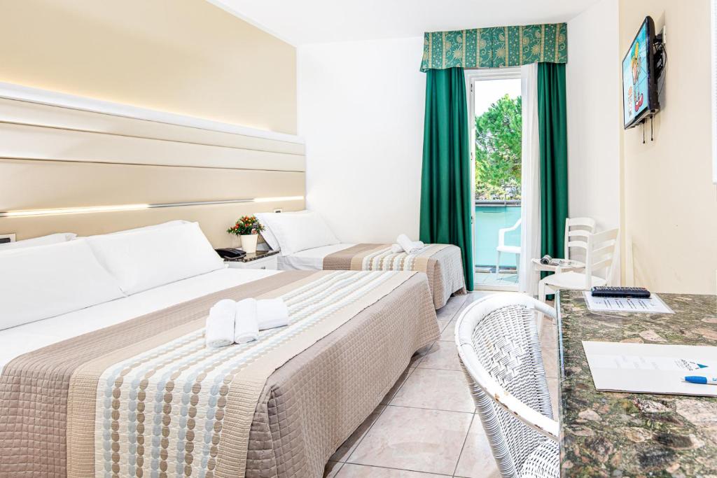 une chambre d'hôtel avec deux lits et un balcon dans l'établissement Hotel Mediterraneo, à Lignano Sabbiadoro