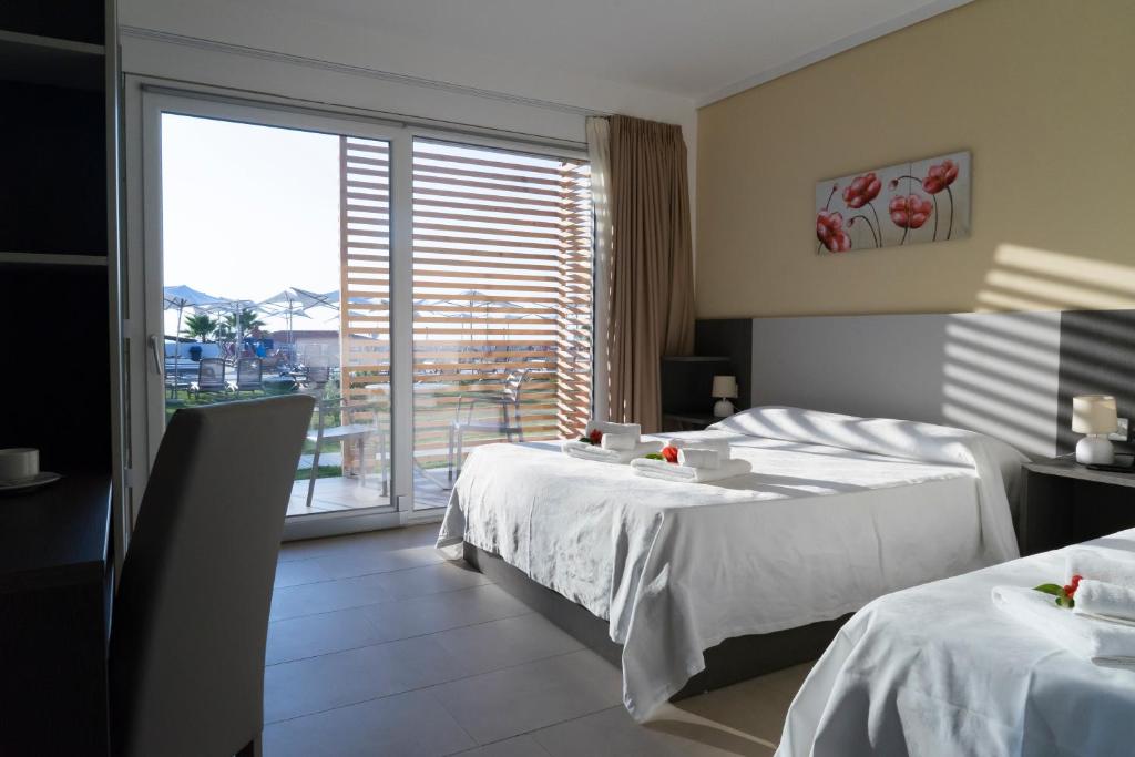 une chambre d'hôtel avec deux lits et une grande fenêtre dans l'établissement TUISuneo La Conchiglia - Adults Only, à Capo Vaticano 115 autres photos