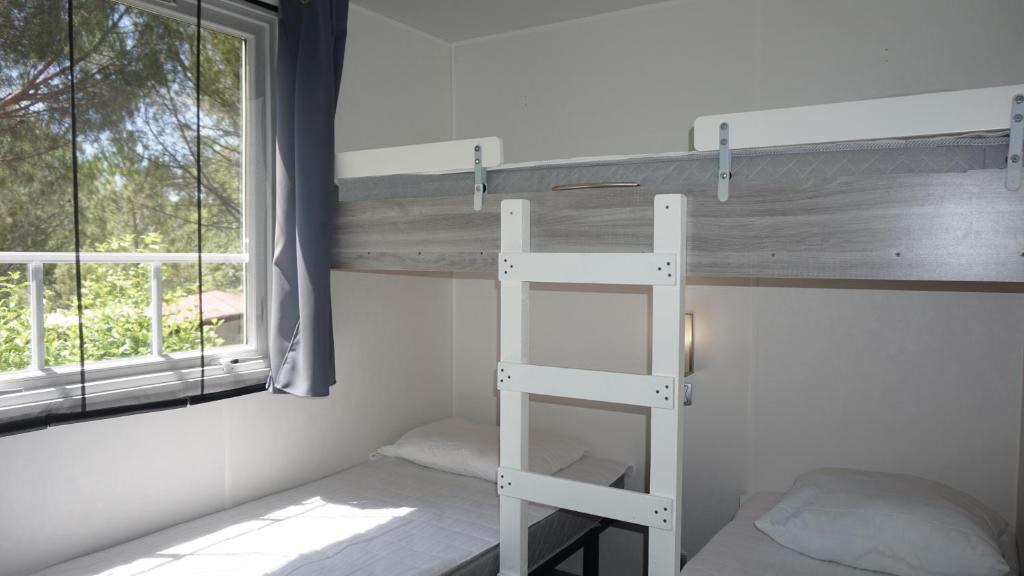 - un lit superposé avec une échelle dans une chambre avec une fenêtre dans l'établissement Luxe chalet voor 5 personen op Camping Leï Suves - JoyCasa, à Roquebrune-sur Argens