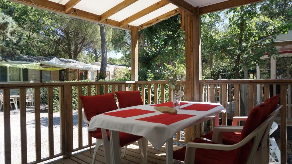 une terrasse couverte en bois avec une table et des chaises. dans l'établissement Luxe chalet voor 5 personen op Camping Leï Suves - JoyCasa, à Roquebrune-sur Argens