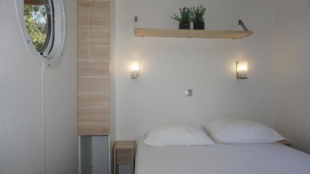 une chambre avec un lit avec des draps blancs et une fenêtre dans l'établissement Luxe chalet voor 5 personen op Camping Leï Suves - JoyCasa, à Roquebrune-sur Argens