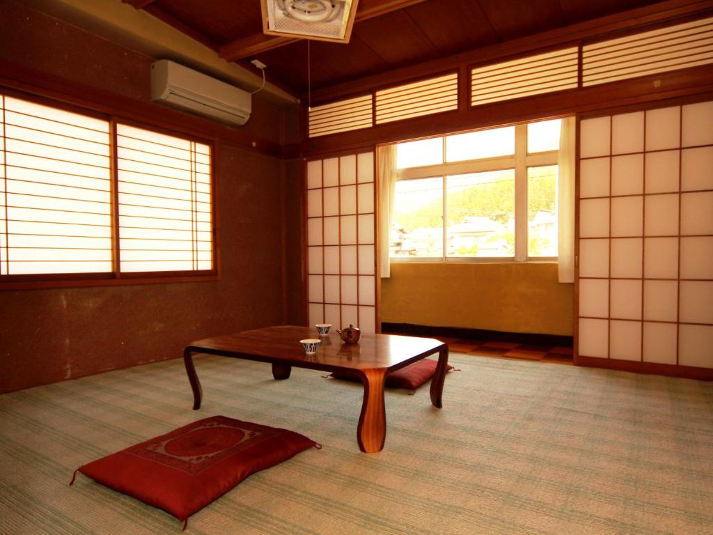une pièce avec une table dans une pièce avec des fenêtres dans l'établissement Minshuku Miyama, à Yamanouchi