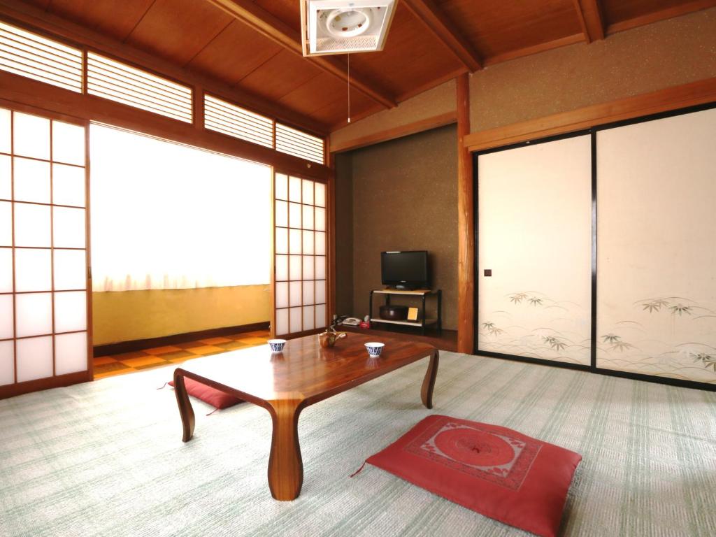 - un salon avec une table en bois et une télévision dans l'établissement Minshuku Miyama, à Yamanouchi