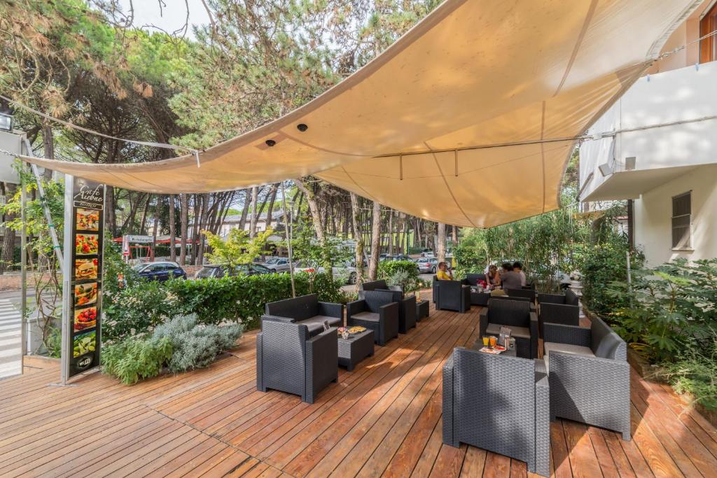 une terrasse en bois avec des chaises et un grand parasol dans l'établissement Hotel Airone, à Bibione