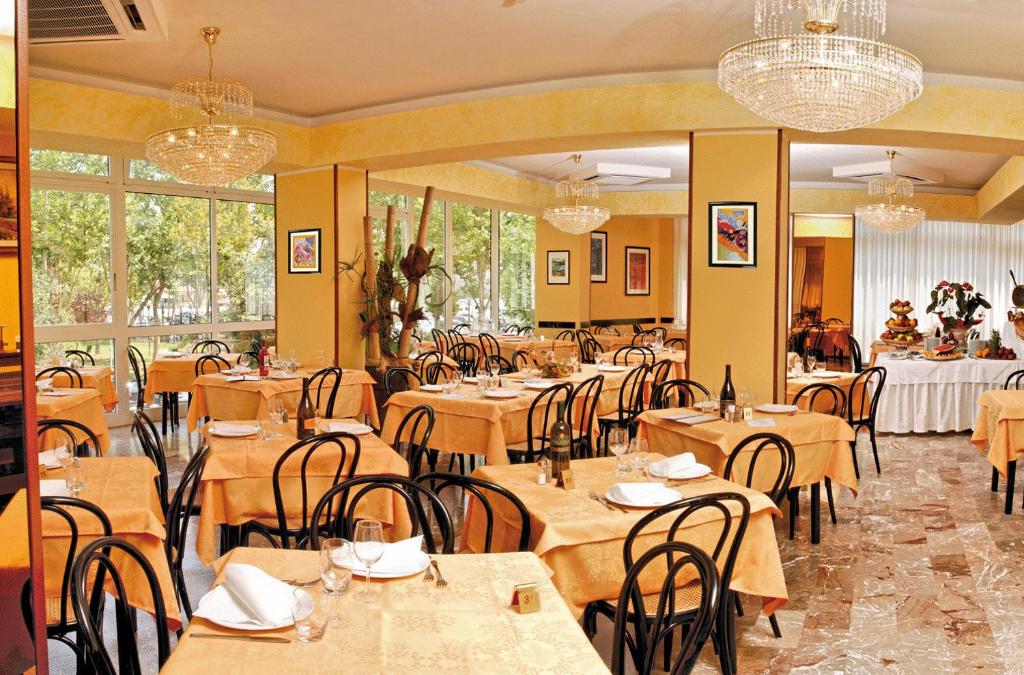 un restaurant avec des tables, des chaises et des lustres en bois dans l'établissement Hotel Imperiale, à Cesenatico