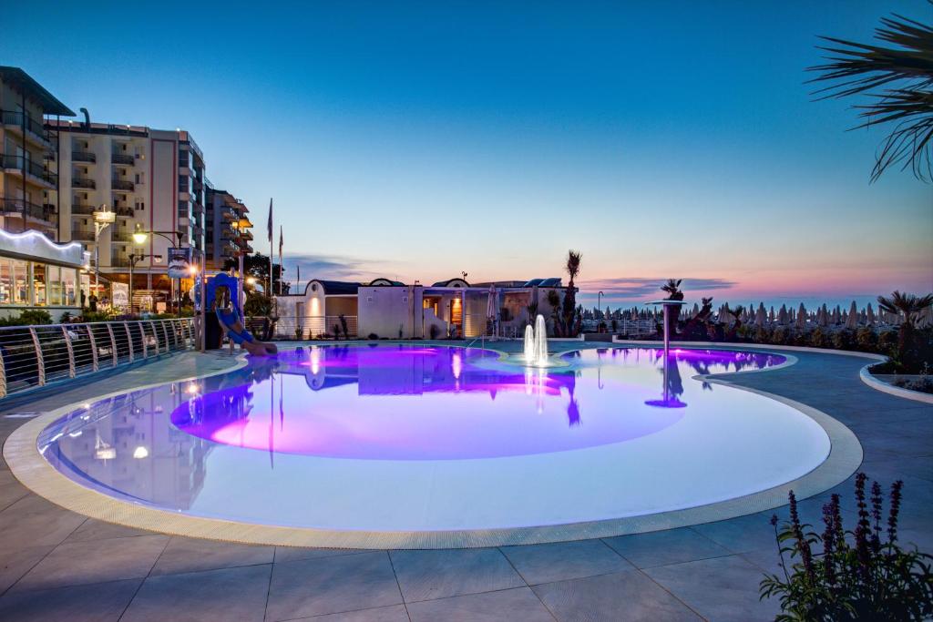 - une grande piscine avec des lumières violettes la nuit dans l'établissement Mediterraneo Hotel & Suites, à Cattolica