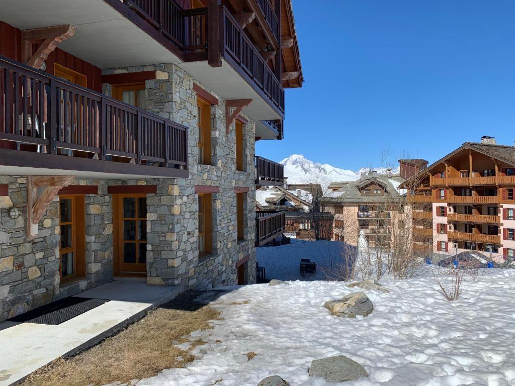 un bâtiment avec de la neige devant une montagne dans l'établissement LE PLUS BEL APPARTEMENT DES ARCS 1950 SKI/PISCINE, à Bourg-Saint-Maurice