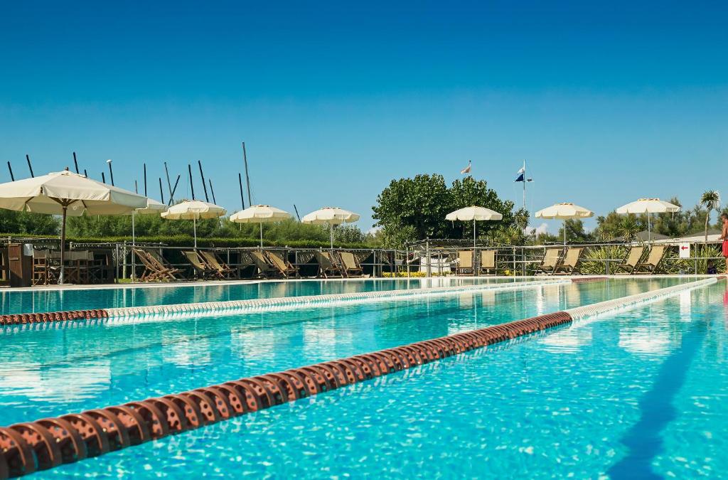 une grande piscine avec chaises et parasols dans l'établissement Oasi del Mare, à Tirrenia