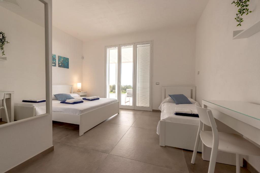 une chambre blanche avec deux lits et un miroir dans l'établissement Villa Iris - IsulaTravel, à Pozzallo