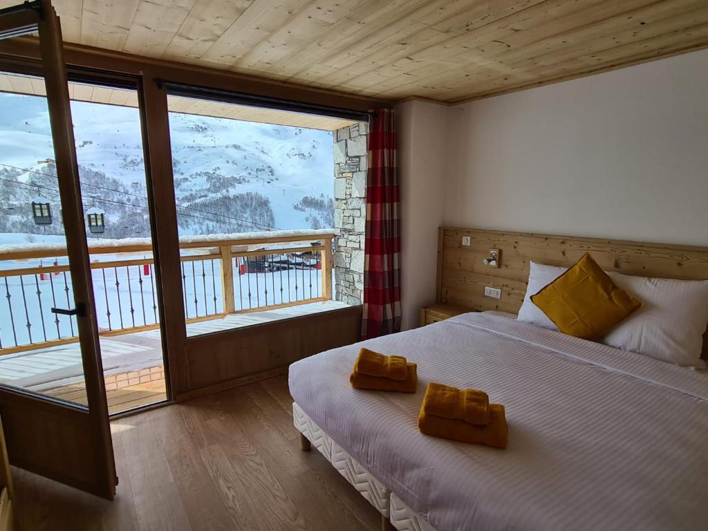 une chambre avec un lit et une grande fenêtre dans l'établissement Chalet Le Granitic, aux Menuires