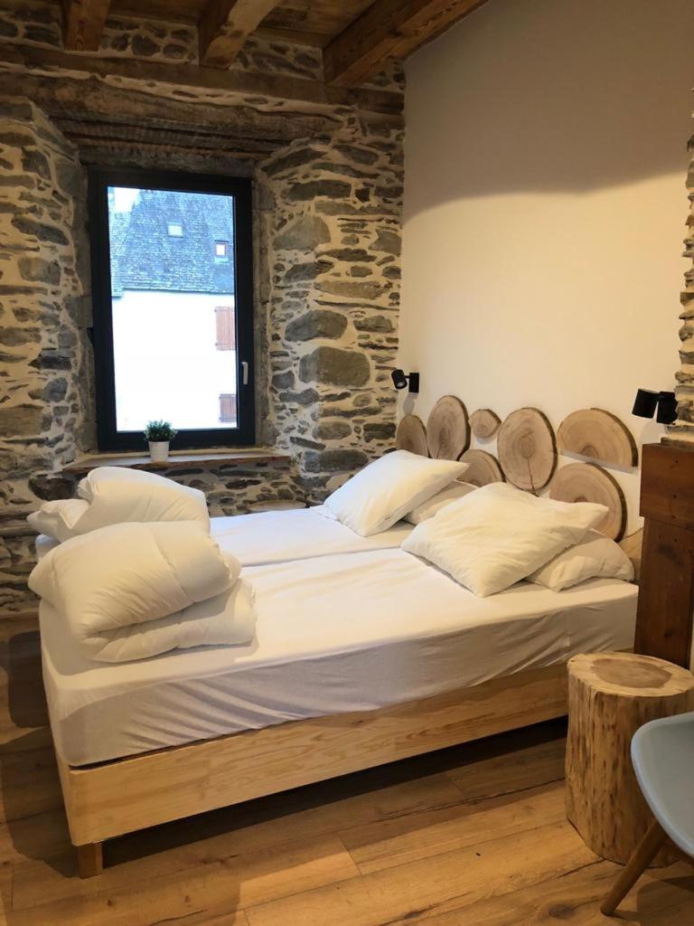 - un grand lit dans une chambre dotée d'un mur en pierre dans l'établissement Les Granges de Clarabide, à Loudenvielle